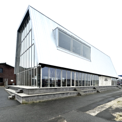 Sideperspektiv af bygning med nyt tag, glas- og metalfacade.