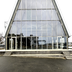 Indgangsparti af bygning med glasfacader og nyt tag.